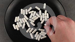 Hand takes white medicine capsules