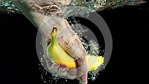 Hand taking a banana from water