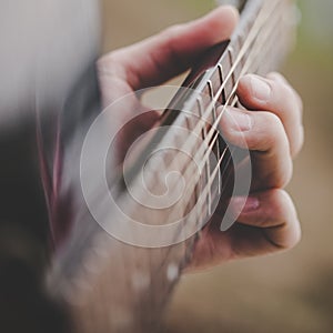 Hand taking a chord on acoustic guitar - close up