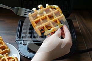 Hand Taking Fresh Waffle from Maker.