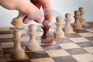 Hand taking his next step on chess game. Human hand moving dark chess pawn piece on chess board