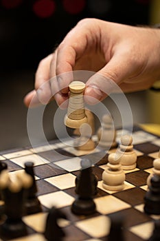 Hand taking next step on chess game. Human hand moving wooden white rook piece