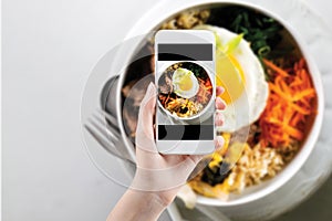 Hand taking a photo of Healthy food with smartphone. Woman using phone mobile apps make digital picture on screen of diet