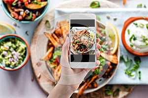 Hand taking a photo of Healthy food with smartphone. Woman using phone mobile apps make digital picture on screen of diet