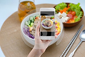 Hand taking a photo of Healthy food with smartphone. Woman using phone mobile apps make digital picture on screen of diet