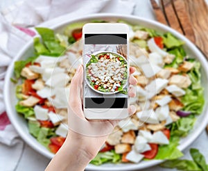 Hand taking a photo of Healthy food with smartphone. Woman using phone mobile apps make digital picture on screen of diet