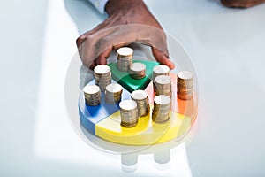 Hand Taking Piece Of Pie Chart With Stack Of Coins