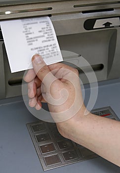 Hand taking receipt out of ATM photo