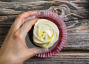 Hand taking rose form muffin on wooden background