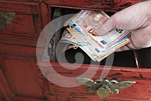 Hand taking stack of paper money from drawer