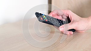 A hand taking TV remote control from the shelf, watching tv broadcast concept