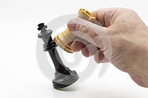 Hand taking white queen chess piece, checkmate black king