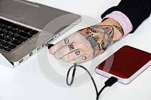 Hand with tattoo connect a external Hdd cable to laptop