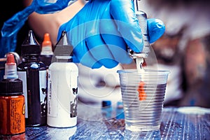 Hand of a tattooer with a tattoo gun.