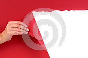 Hand tearing red paper background revealing white copy space