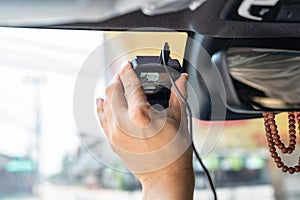 Hand of technician installing front camera car recorder on windscreen