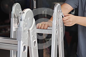 Hand of technician locking Folding Ladder In the open position . convenient ladders ,Light weight, these ladders fold into a compa