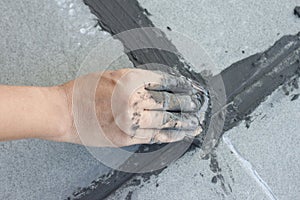 Hand of technician use of rubber flooring on gray color of new grout tile.