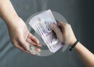 The hand of the tenant extends money to landlords exchange with the room key