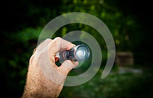 Hand testing holding new mini flashlight torch green defocused outdoor