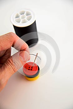 Hand threading a needle with black thread