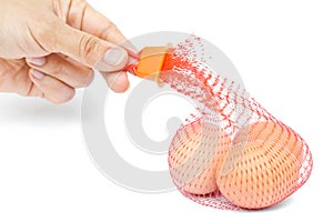 Hand and three eggs in a mesh bag.