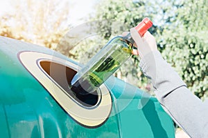 Hand throwing glass bottle in recycling bin