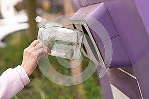 Hand throwing a glass jar into a container for separate garbage collection in Israel