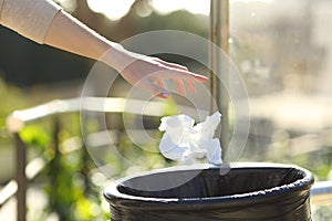 Hand throwing litter into bin in a park