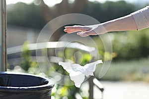 Hand throwing litter outside a bin in a park