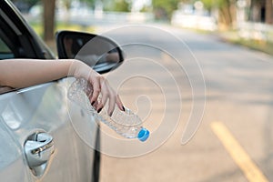 Hand throwing plastic bottle on the road