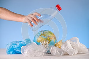 Hand is throwing the plastic on the Earth that is in a pile of garbage. Environmental pollution and saving the planet