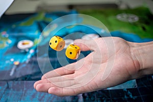 The hand throws yellow dice on the playing field. Luck and excitement. Concept Board games