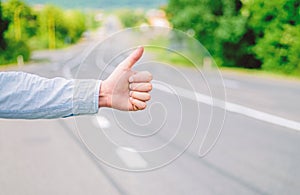 Hand thumb up gesture try stop car road background. Thumb or hand gesture hitchhiking. Make sure you know right gestures