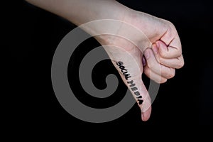 Hand in thumbs down gesture with words social media written on thumb against black background