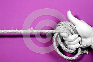 Hand tied with rope on purple background