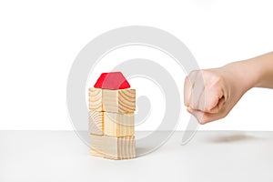 Hand about to destroy house made of wooden blocks photo