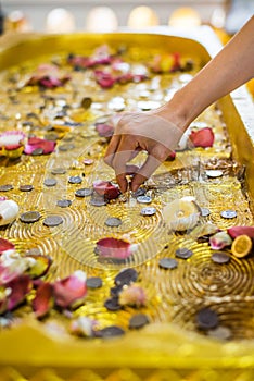 Hand to trying to set a coin baht on image of buddha& x27;s footprint