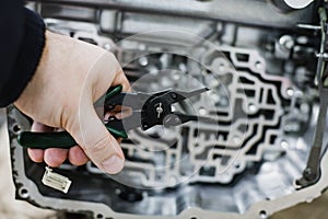 Hand with tool against the background of an automatic transmission with shallow depth of field