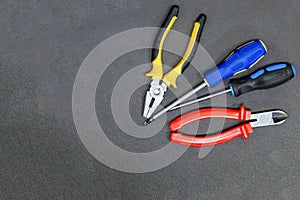 Hand tool red wire nippers screwdriver fixation repair on a dark background copy space