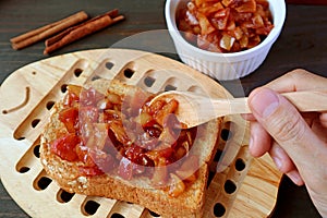 Hand topping a whole grain toast with delectable homemade apple cinnamon compote