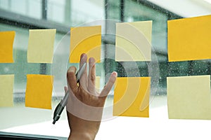 hand touch on adhesive notes on glass wall. Sticky note paper re