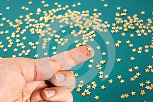 Hand touches solid confetti in the form stars. The concept of touch, tactility, feelings