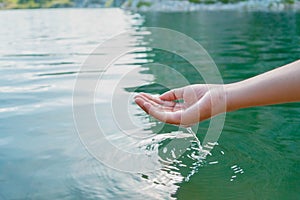 hand touches water in pond with sunshine