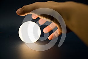 Hand touching a bright ball