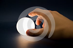 Hand touching a bright ball