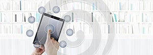 Hand touching digital tablet with icons isolated in library background