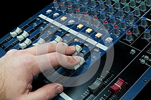 Hand touching faders in an audio mixing console