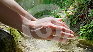 Hand touching flowing stream water.