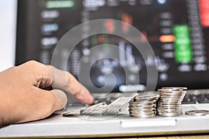 Hand touching keyboard and coin with monitor shows trading traffic, Bitcoin minning
